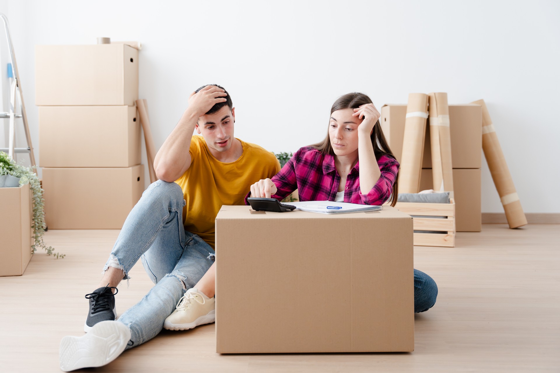 Young couple calculating expenses in empty house